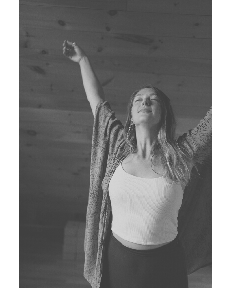 black and white portrait of Naomi Elder smiling with eyes closed both arm up in the air